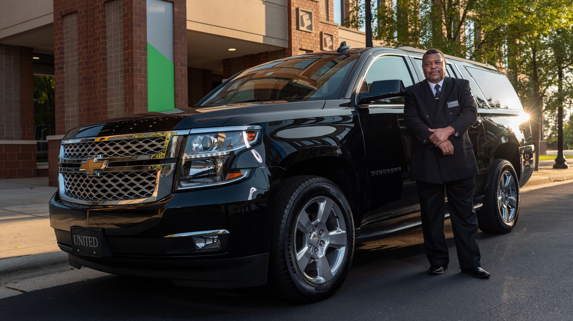 Professional chauffeur beside a black SUV